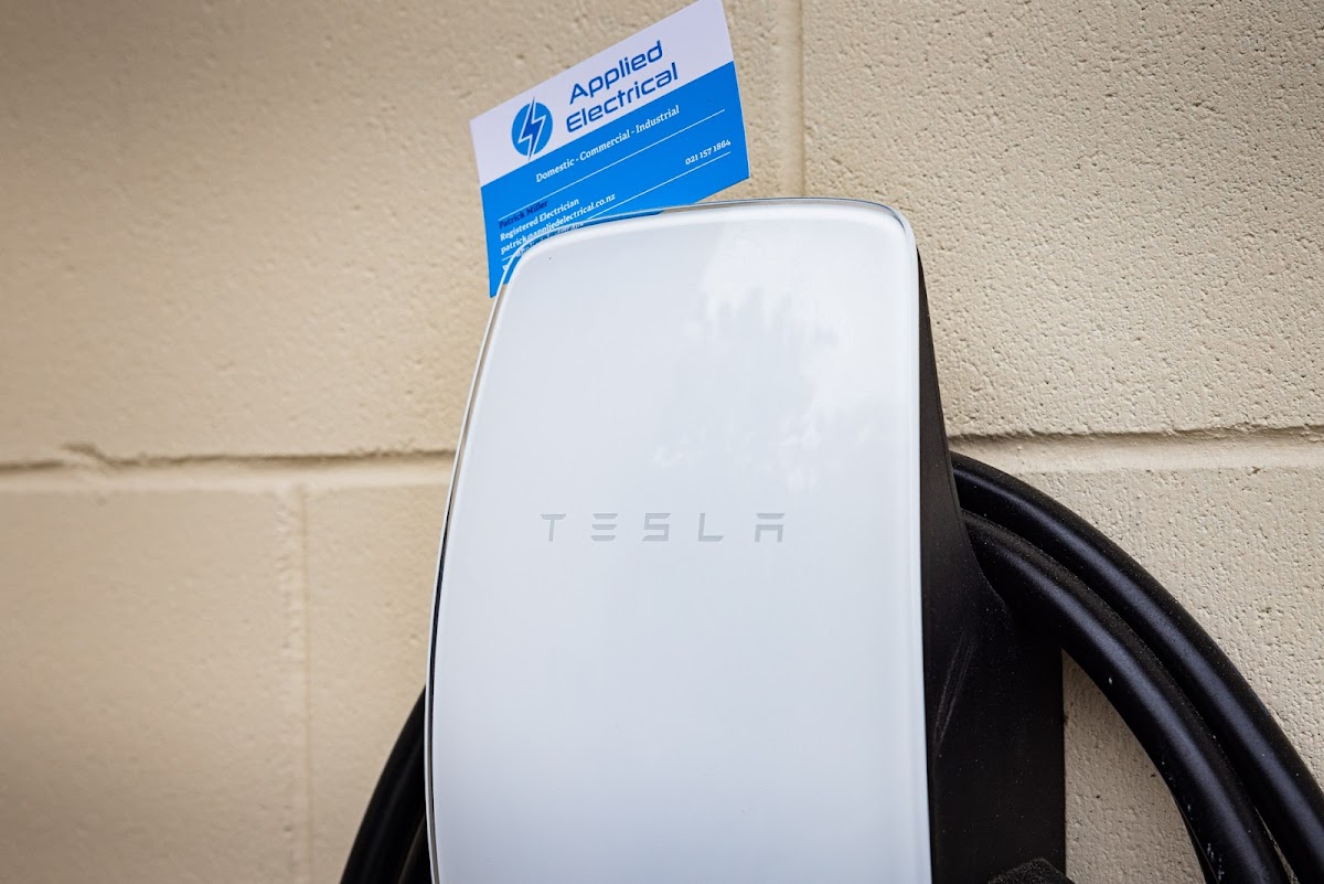 Tesla EV charger installed by Applied Electrical with business card